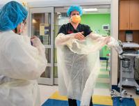 Healthcare worker putting on protective gown.